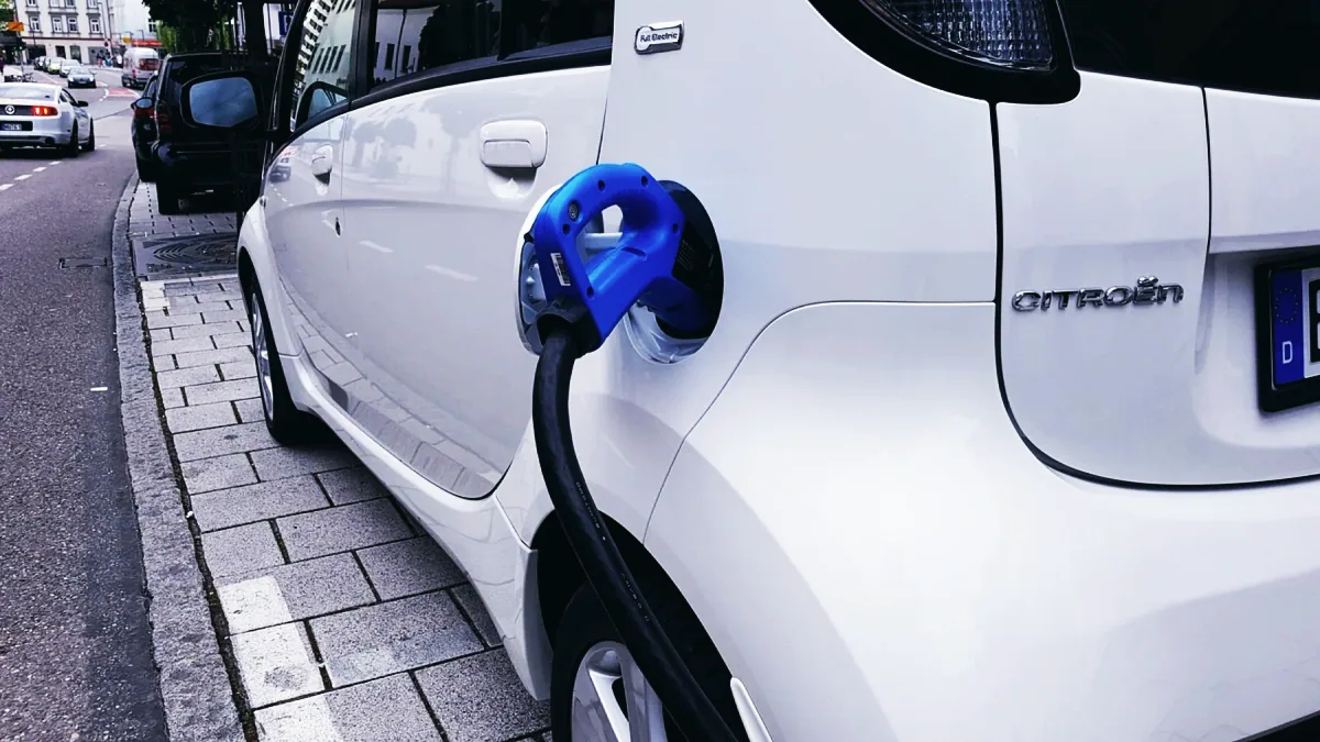 Vit elbil parkerad vid en laddstolpe på en arbetsplatsparkering i Sverige.