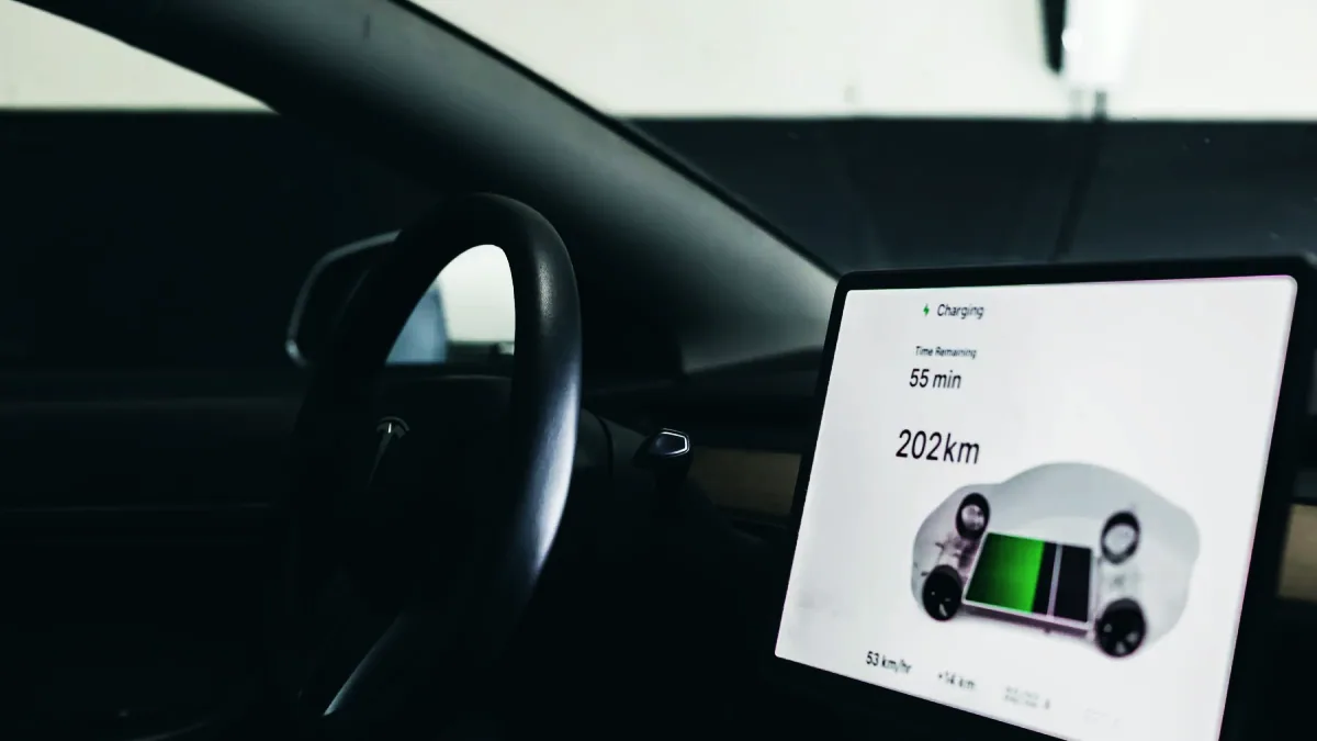 Mekaniker håller en diagnosplatta kopplad till bilens OBD-uttag och läser av batterihälsan på en elbil.