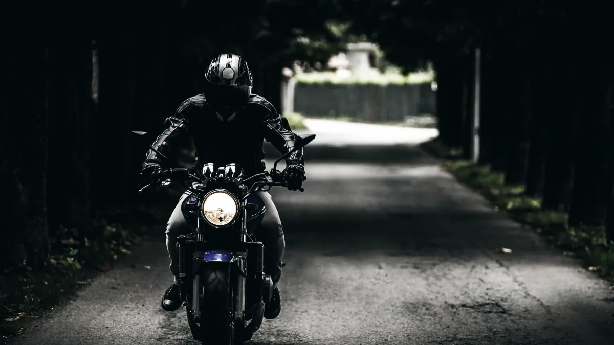Motorcyklist i hel skinnställ och hjälm vid startpunkten för körprovet, med en instruktör bredvid.