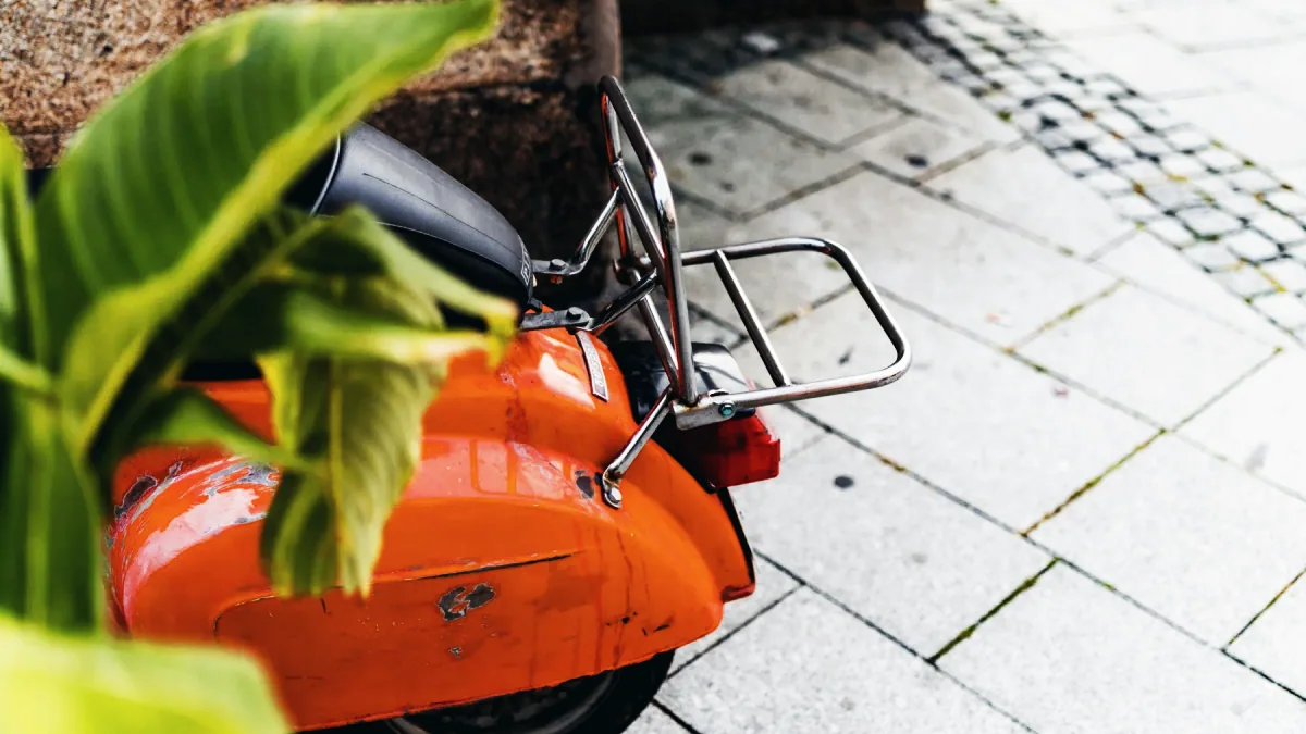 Moped bakifrån med liten registreringsskylt, parkerad intill en skylt för cykelbana.