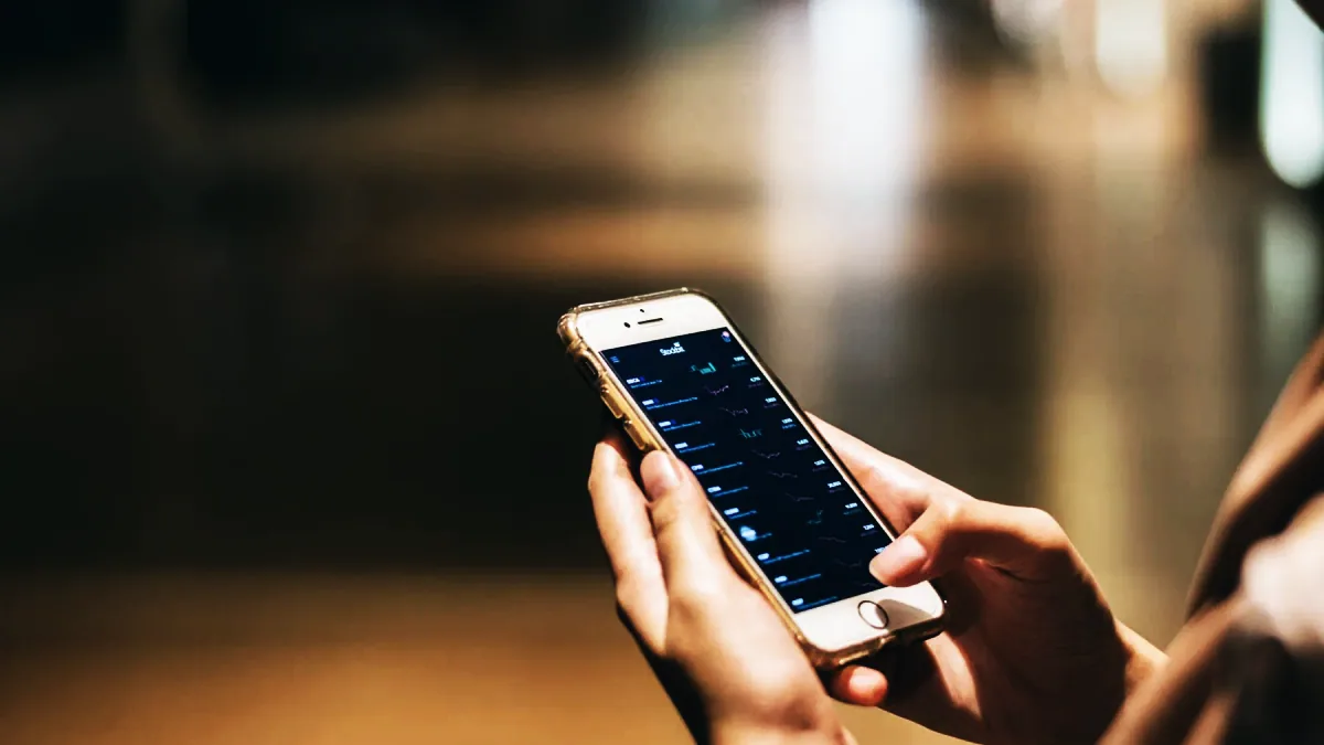 Säljare står bredvid bilen och kontrollerar i mobilens bankapp att betalningen har kommit in.