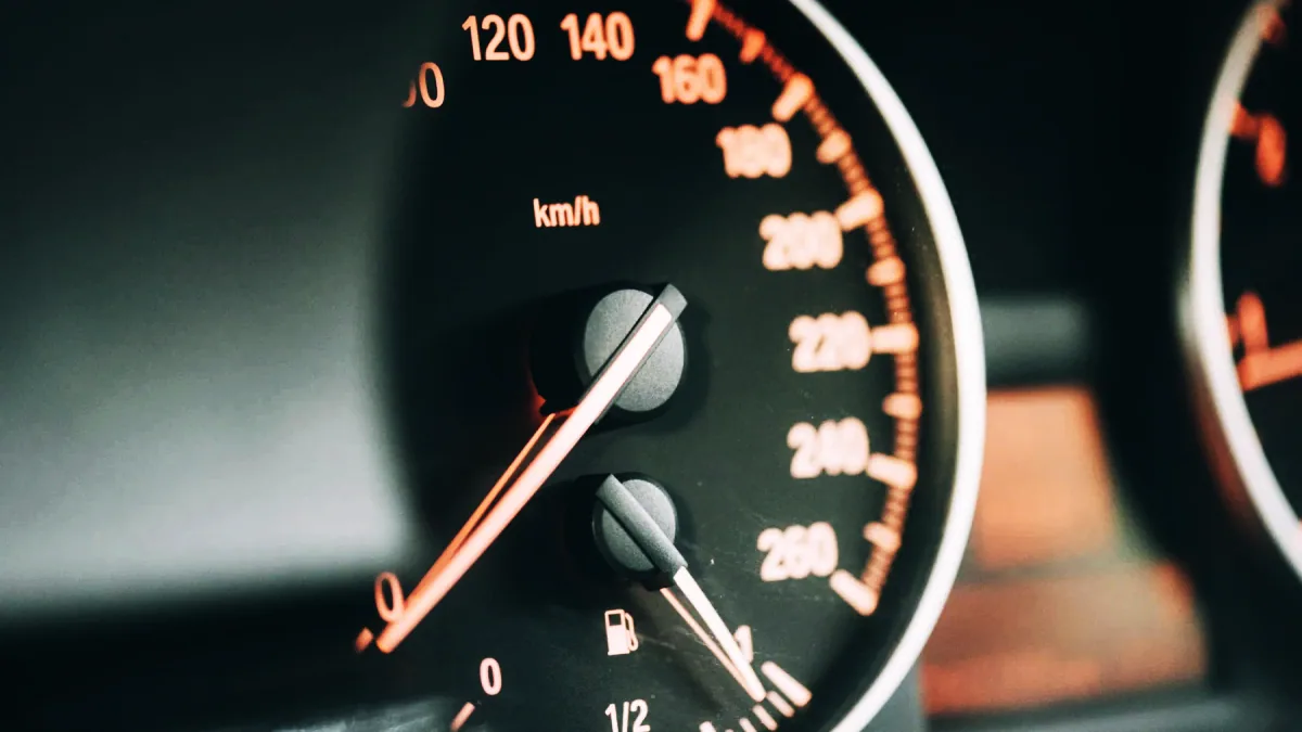 Närbild på en hastighetsmätare i en bil där nålen passerar 90 km/h i mörker.